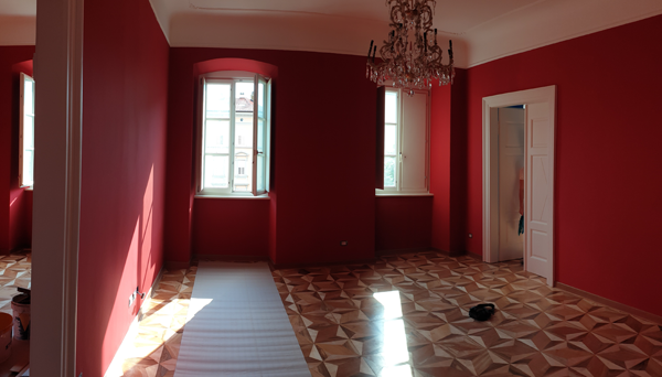 Stanza rifinita con pareti rosse e parquet a spina di pesce